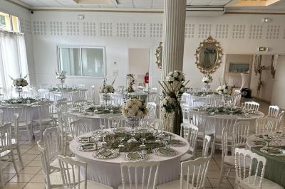 Table élégamment dressée avec vaisselle raffinée, centre de table floral et décoration lumineuse en arrière-plan.