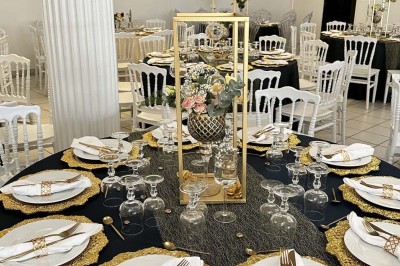 Table élégamment dressée avec vaisselle raffinée, centre de table floral et décoration lumineuse en arrière-plan.