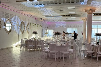 Table élégamment dressée avec vaisselle raffinée, centre de table floral et décoration lumineuse en arrière-plan.