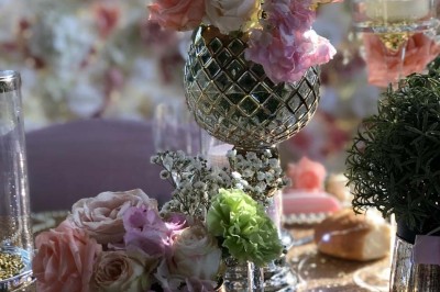 Table élégamment dressée avec vaisselle raffinée, centre de table floral et décoration lumineuse en arrière-plan.