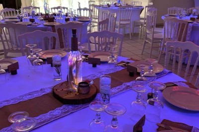 Table élégamment dressée avec vaisselle raffinée, centre de table floral et décoration lumineuse en arrière-plan.