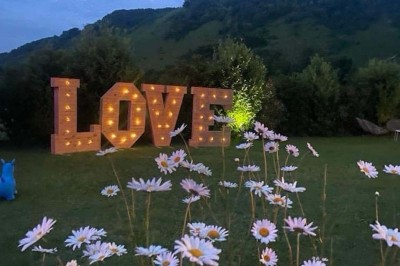 Table élégamment dressée avec vaisselle raffinée, centre de table floral et décoration lumineuse en arrière-plan.