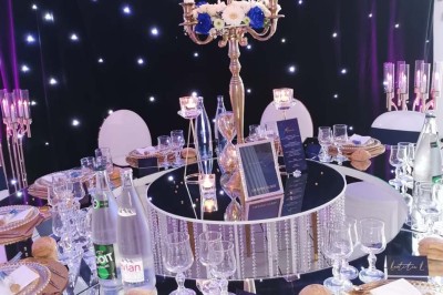 Table élégamment dressée avec vaisselle raffinée, centre de table floral et décoration lumineuse en arrière-plan.