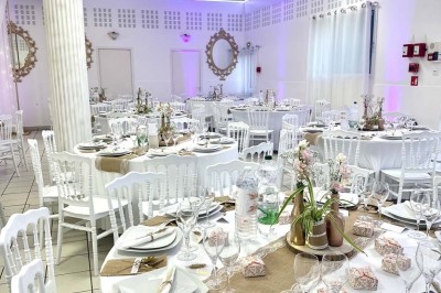 Table élégamment dressée avec vaisselle raffinée, centre de table floral et décoration lumineuse en arrière-plan.