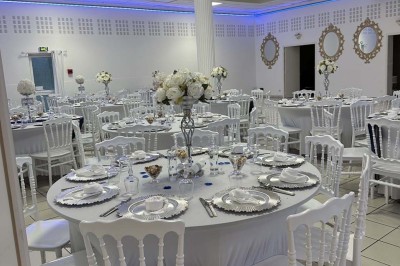 Table élégamment dressée avec vaisselle raffinée, centre de table floral et décoration lumineuse en arrière-plan.