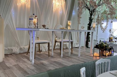 Table élégamment dressée avec vaisselle raffinée, centre de table floral et décoration lumineuse en arrière-plan.