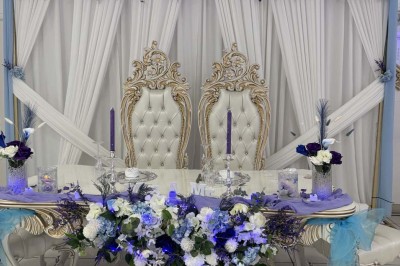 Table élégamment dressée avec vaisselle raffinée, centre de table floral et décoration lumineuse en arrière-plan.