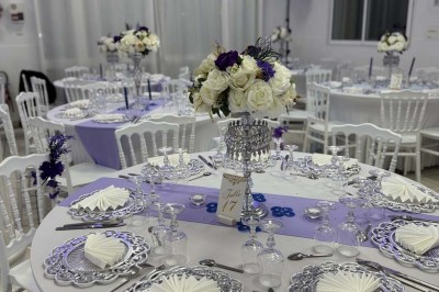 Table élégamment dressée avec vaisselle raffinée, centre de table floral et décoration lumineuse en arrière-plan.