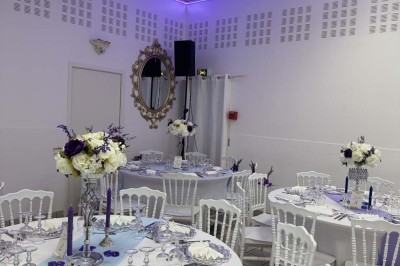 Table élégamment dressée avec vaisselle raffinée, centre de table floral et décoration lumineuse en arrière-plan.