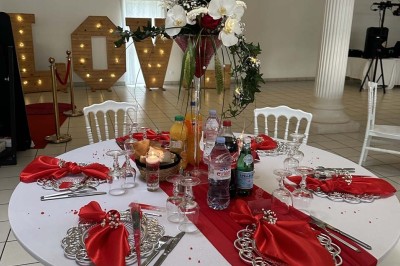 Table élégamment dressée avec vaisselle raffinée, centre de table floral et décoration lumineuse en arrière-plan.