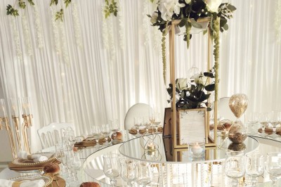 Table élégamment dressée avec vaisselle raffinée, centre de table floral et décoration lumineuse en arrière-plan.