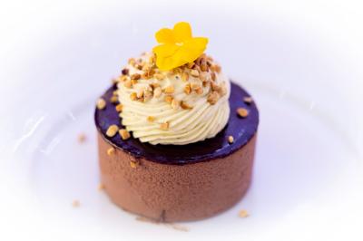 Dessert pyramidal en fromage blanc accompagné de fraises tranchées et d'une fleur comestible sur une assiette blanche.