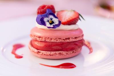 Dessert pyramidal en fromage blanc accompagné de fraises tranchées et d'une fleur comestible sur une assiette blanche.