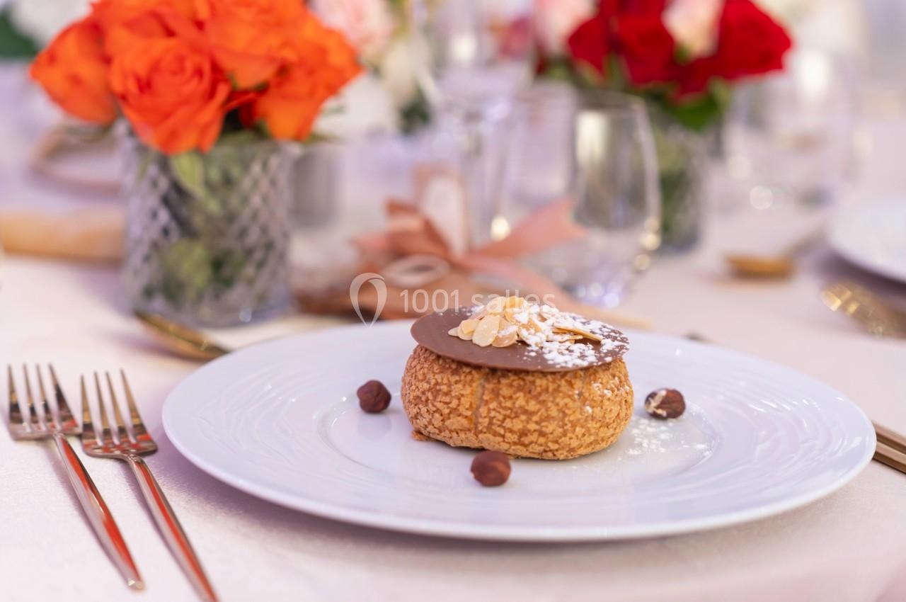 Pâtisserie garnie de chocolat et d'amandes sur une assiette blanche, entourée de décorations de table élégantes.