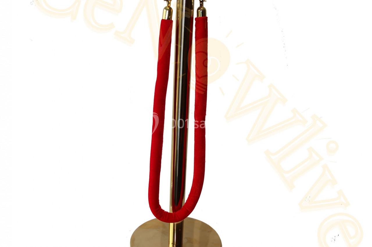 Poteau doré avec corde rouge, utilisé pour délimiter des espaces ou organiser des files d'attente.
