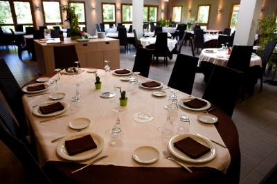 Salle de restaurant lumineuse avec tables dressées, nappes blanches, chaises noires et grandes fenêtres donnant sur l…