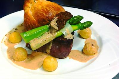 Des personnes préparent et disposent des desserts sur des assiettes alignées dans une cuisine professionnelle.