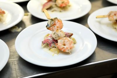 Des personnes préparent et disposent des desserts sur des assiettes alignées dans une cuisine professionnelle.