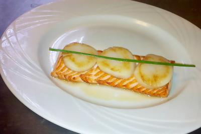 Des personnes préparent et disposent des desserts sur des assiettes alignées dans une cuisine professionnelle.