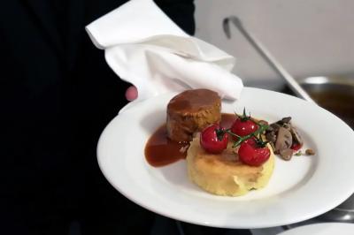 Des personnes préparent et disposent des desserts sur des assiettes alignées dans une cuisine professionnelle.