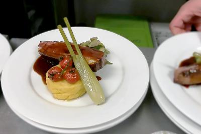 Des personnes préparent et disposent des desserts sur des assiettes alignées dans une cuisine professionnelle.