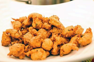 Des personnes préparent et disposent des desserts sur des assiettes alignées dans une cuisine professionnelle.