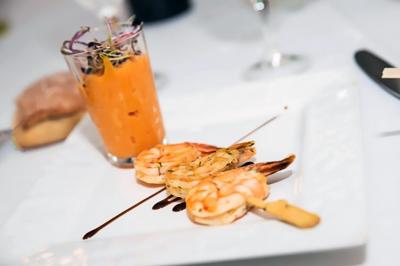 Des personnes préparent et disposent des desserts sur des assiettes alignées dans une cuisine professionnelle.