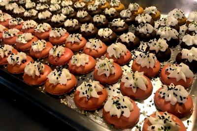 Des personnes préparent et disposent des desserts sur des assiettes alignées dans une cuisine professionnelle.