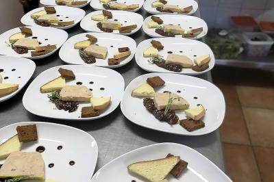Des personnes préparent et disposent des desserts sur des assiettes alignées dans une cuisine professionnelle.