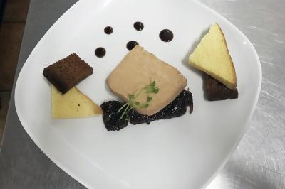 Des personnes préparent et disposent des desserts sur des assiettes alignées dans une cuisine professionnelle.