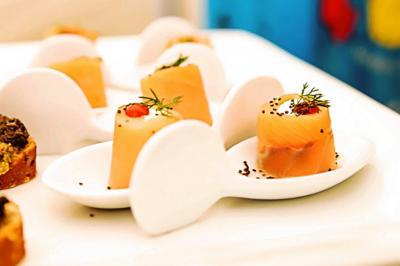 Des personnes préparent et disposent des desserts sur des assiettes alignées dans une cuisine professionnelle.