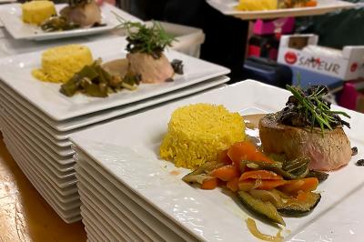 Des personnes préparent et disposent des desserts sur des assiettes alignées dans une cuisine professionnelle.