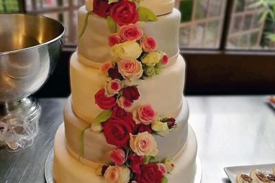 Des personnes préparent et disposent des desserts sur des assiettes alignées dans une cuisine professionnelle.