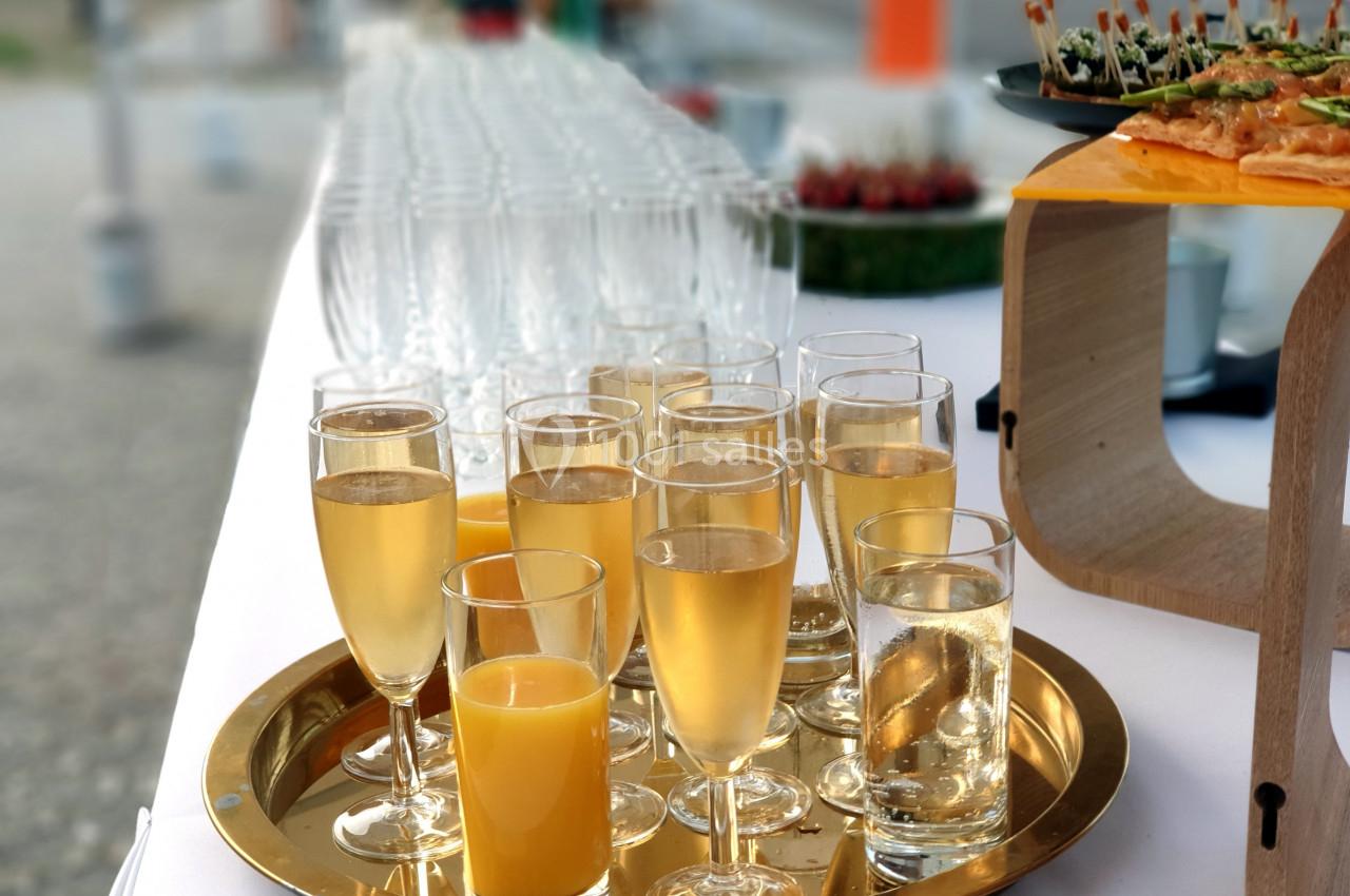 Plateau de boissons comprenant des verres de jus d'orange et de champagne, disposé sur une table blanche.