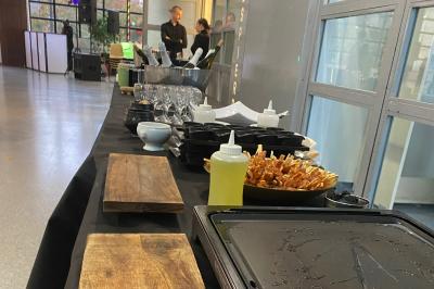 Des personnes préparent et disposent des desserts sur des assiettes alignées dans une cuisine professionnelle.