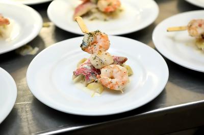 Brochette de crevettes et pétoncles servie sur un lit de légumes, présentée sur une assiette blanche.