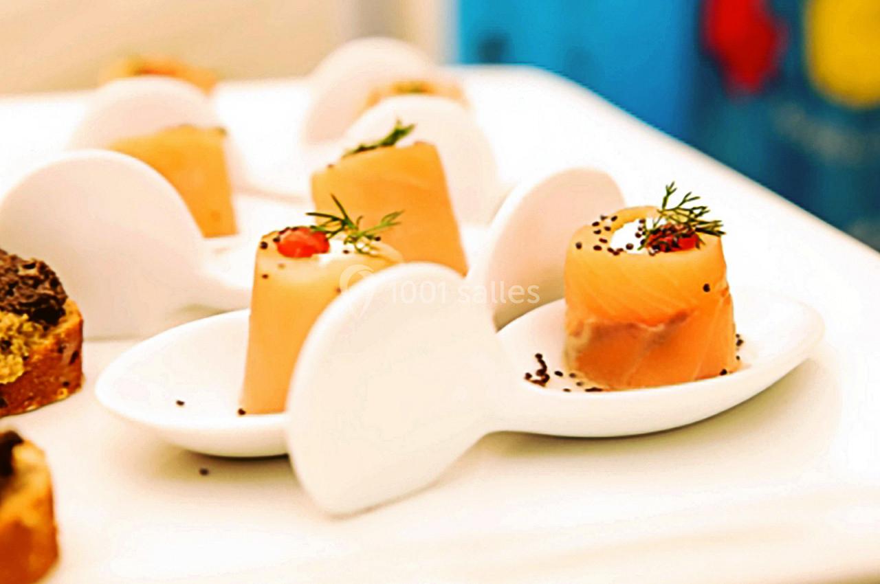 Bouchées de saumon fumé garnies de crème et d'herbes, présentées sur des cuillères blanches.