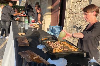 Des personnes préparent et dressent des assiettes avec des desserts dans une cuisine professionnelle.