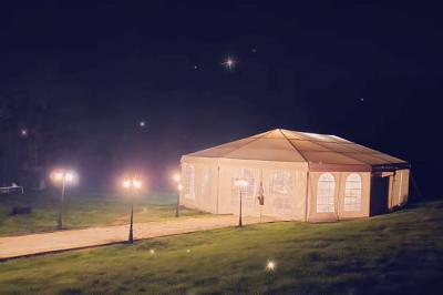 Vue d'un espace extérieur avec pelouse, structures gonflables colorées et arbres en arrière-plan, sous un ciel bleu.