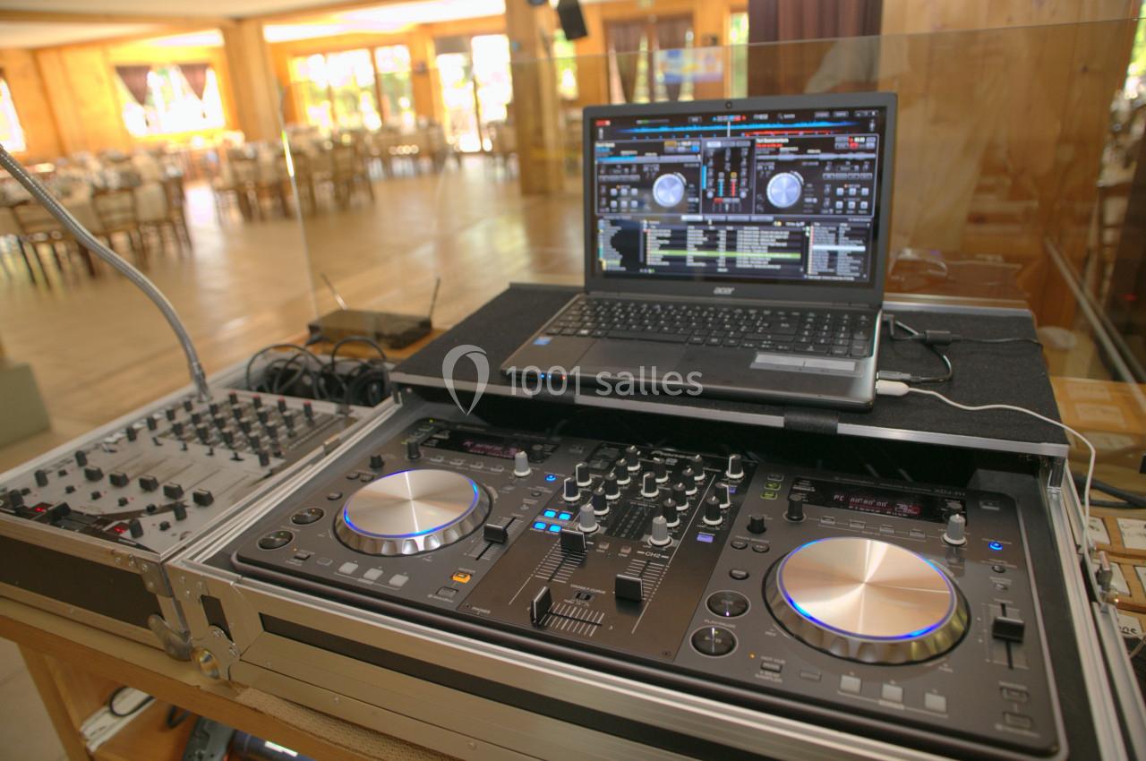 Table de mixage avec platines et ordinateur portable affichant un logiciel de DJ, installée dans une salle lumineuse.