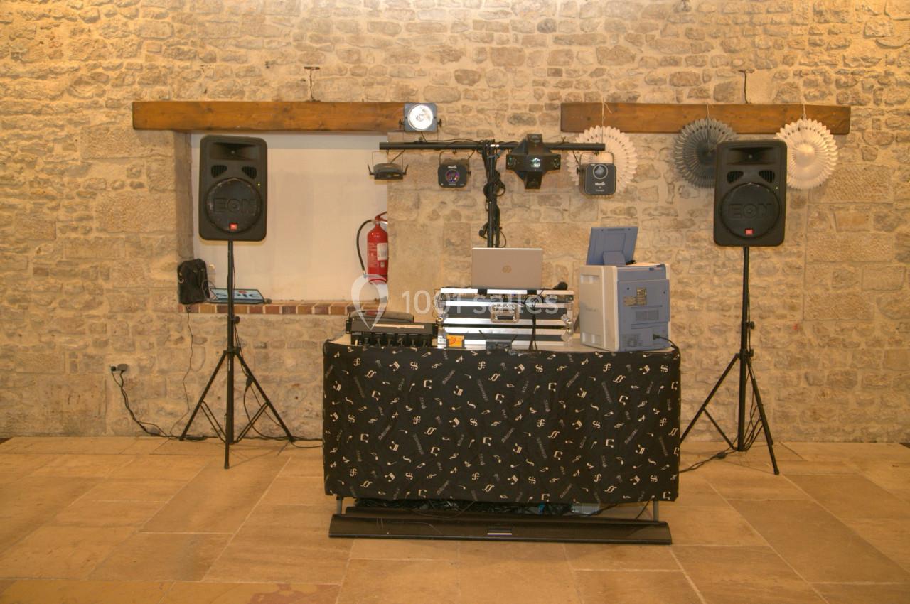 Installation de matériel de sonorisation et d'éclairage dans une salle en pierre avec une table recouverte d'un tissu noir.