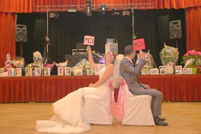 Un couple assis dos à dos lors d'une fête, chacun tenant une pancarte ’MOI’, entouré de décorations et de cadeaux.