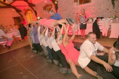 Des personnes assises en ligne dans une salle de réception portent une femme allongée au-dessus d'elles.