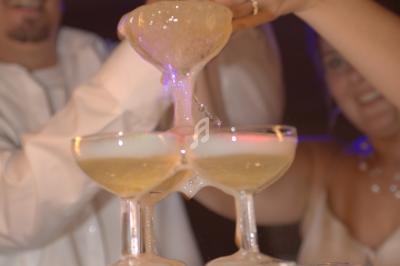 Une personne verse du champagne dans une pyramide de coupes en verre lors d'une célébration festive.