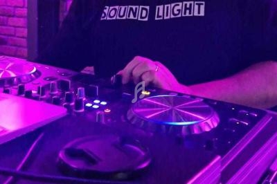 Personne ajustant les commandes d'une table de mixage DJ sous un éclairage violet.