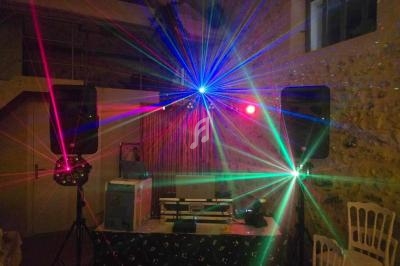 Effets lumineux colorés avec lasers et projecteurs dans une salle en pierre, entourés d'équipements de sonorisation.