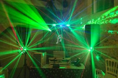 Installation de matériel de sonorisation et jeux de lumières colorées dans une salle en pierre.