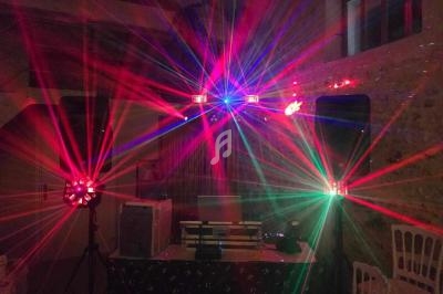 Effets lumineux colorés de projecteurs et lasers dans une salle sombre avec des murs en pierre.