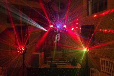 Jeu de lumières colorées projetées dans une salle sombre avec un équipement de sonorisation en arrière-plan.