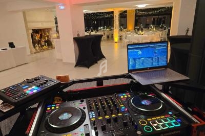 Poste de DJ avec platines et ordinateur portable dans une salle de réception décorée pour un événement festif.